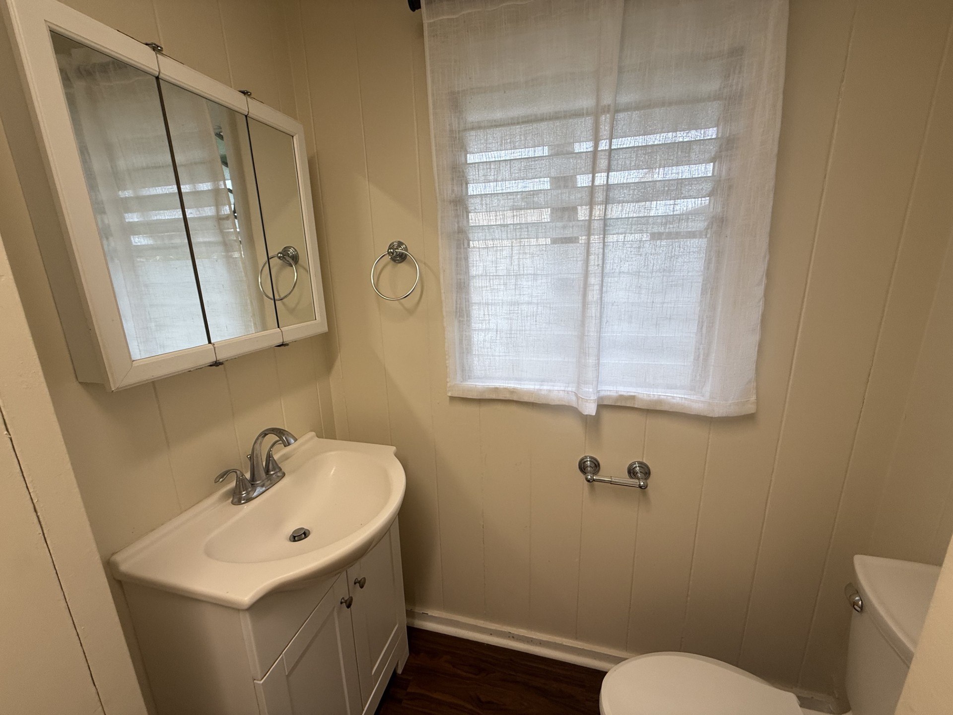 A white sink in a small bathroom with a window.